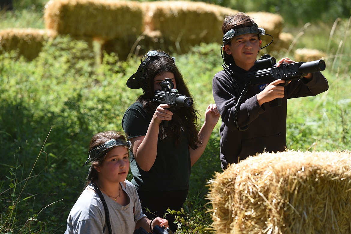 Layla Blumenthal, left, Alexa Blumenthal, middle, and Jack Nortman take cover together during a round of laser tag with Flashpoint Outdoor Laser Tag near Bigfork on Friday, Aug. 10, 2021. (Jeremy Weber/Daily Inter Lake)