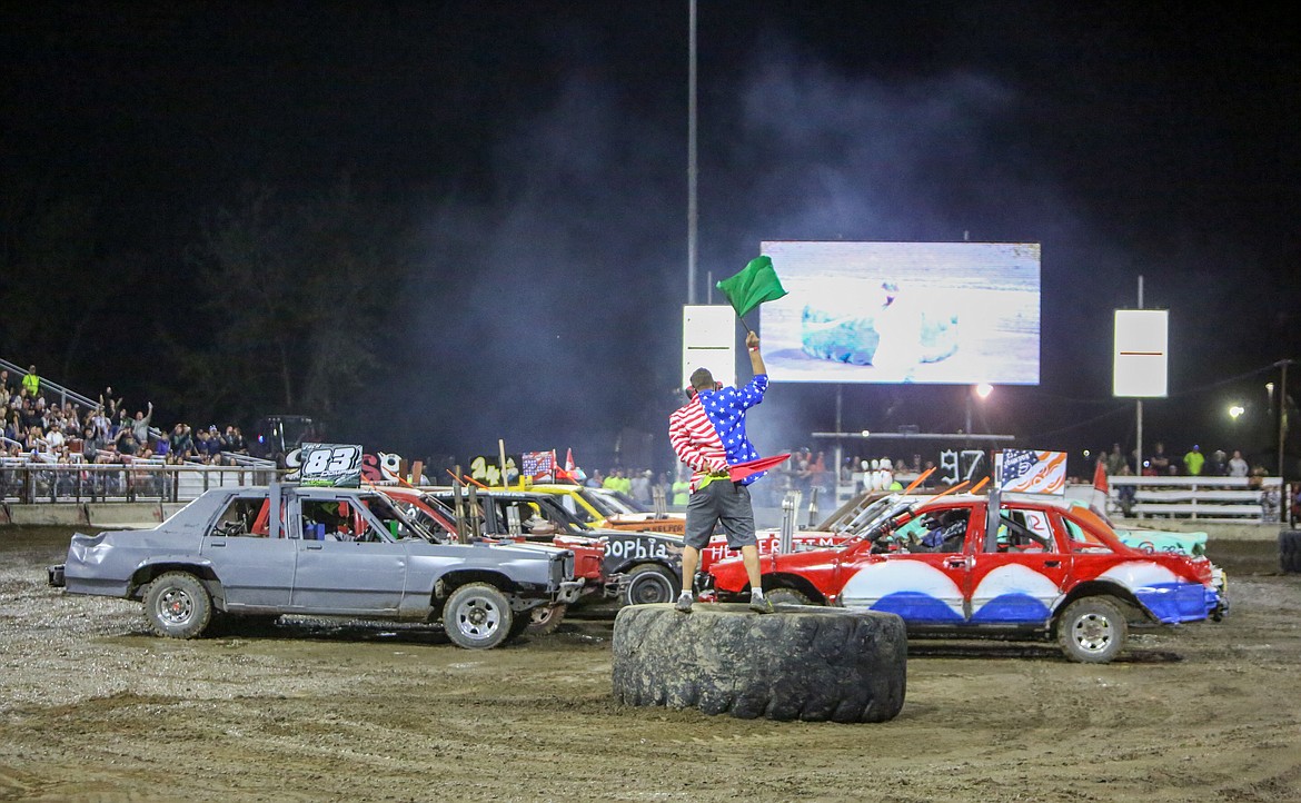 Flagman Brandon Douglass waves the green flag to signal the start of the demolition derby on Wednesday night at the Northwest Ag Demolition Derby in Moses Lake.