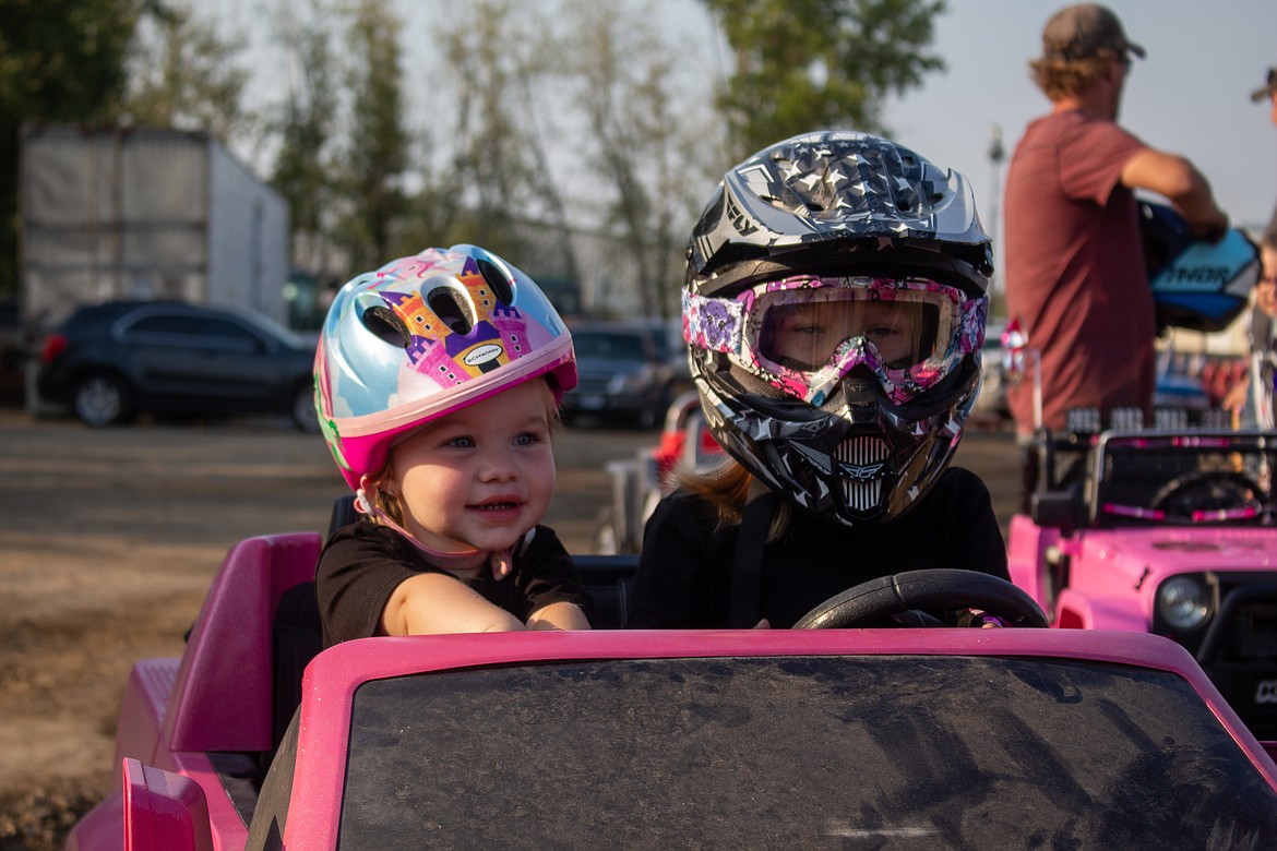 Harper and Amberlee Whitaker smile as they wait for the Youth Power Wheels Demo to begin on Wednesday at the Northwest Ag Demolition Derby.