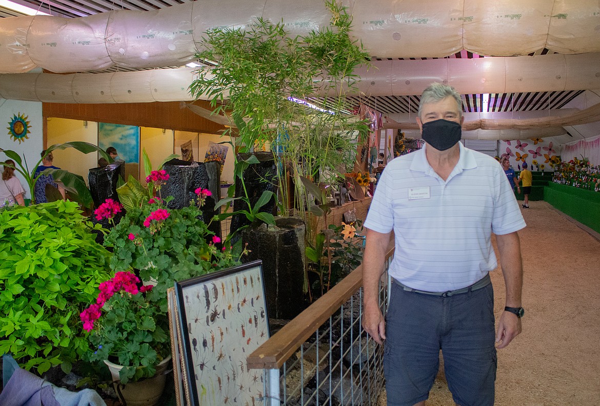 Washington State University Master Gardener Glenn Martin stands in front of flowers and plants on display in the Flower Building at the Grant County Fairgrounds on Wednesday afternoon.