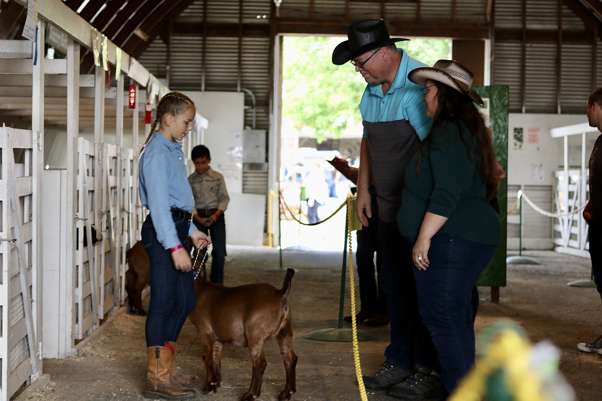 Jersey Larson, left, an 11 year old member of the Country Roots 4-H club, talks with fair-goers in the market goat barn at the North Idaho State Fair on Saturday morning. HANNAH NEFF/Press