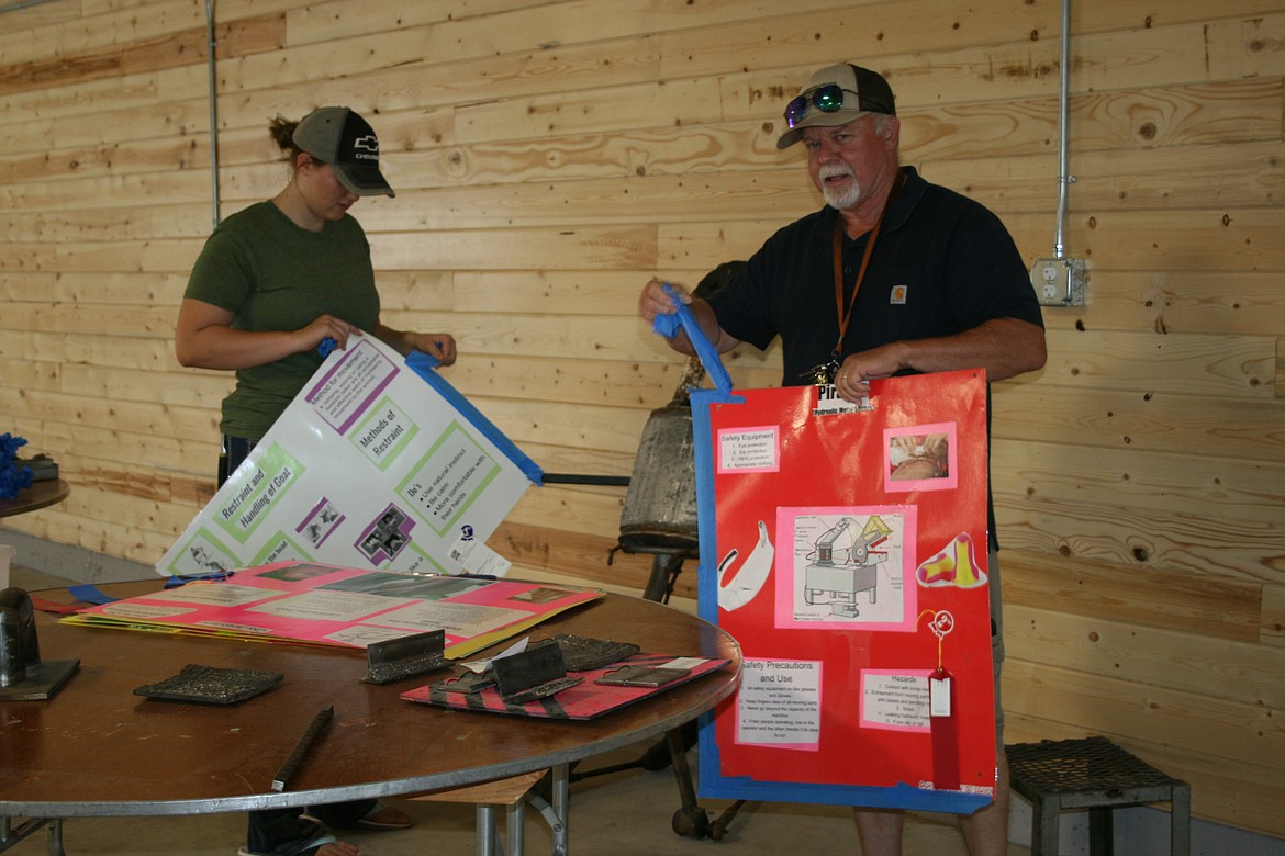 Mia Reeve (left), Ephrata FFA, and Kent Devine, Ephrata FFA adviser, remove posters in the Agricultural Building after the Grant County Fair Sunday.