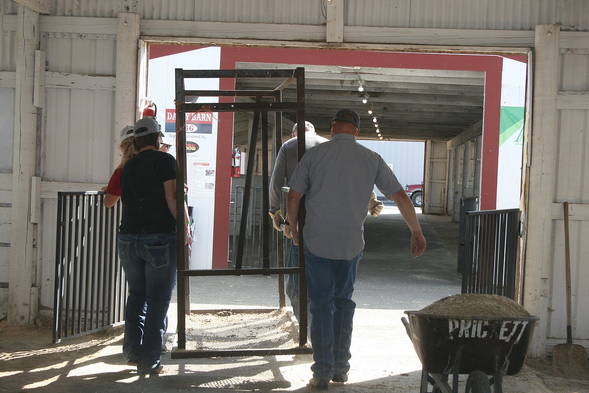 Volunteers remove equipment from the cow barn at the Grant County Fairgrounds Sunday morning.