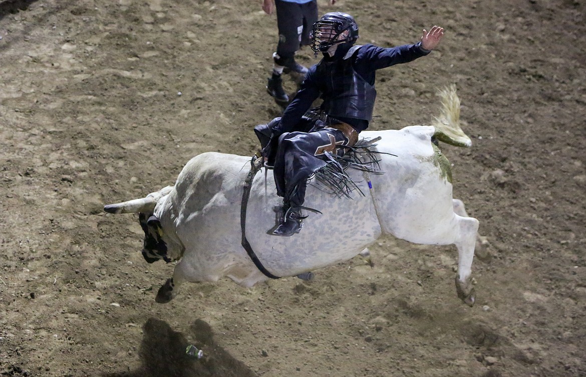 Trevor Reiste of Linden, Iowa, holds on as best he can during the bull riding event at the Grant County Fairgrounds Saturday night at the Moses Lake Roundup Rodeo.