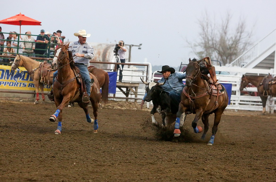 Julius Figeuroa takes the steer to the ground after leaping from his horse in the steer wrestling event Saturday night at the Moses Lake Roundup Rodeo.