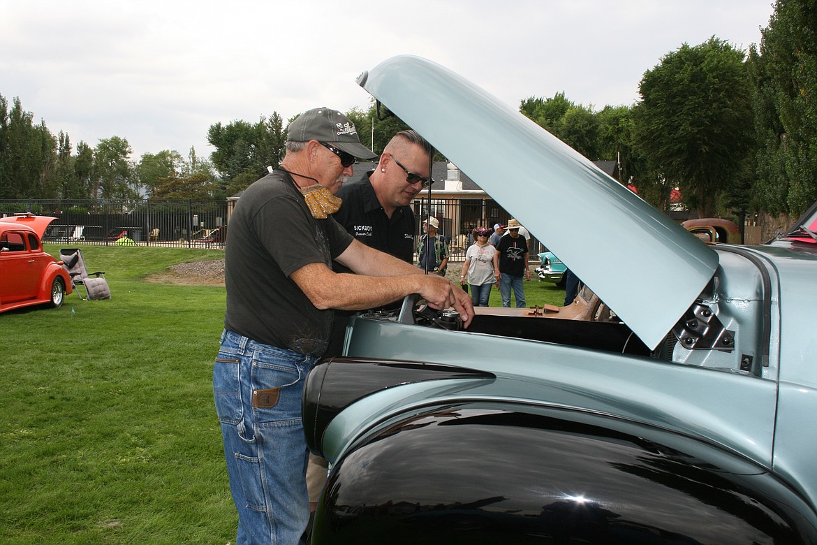 Ray Kramer (left) shows the engine of his 1948 Studebaker truck to fellow car enthusiast Larry Camden at the Hot August Nights car show at Smokiam RV Resort in Soap Lake Saturday.