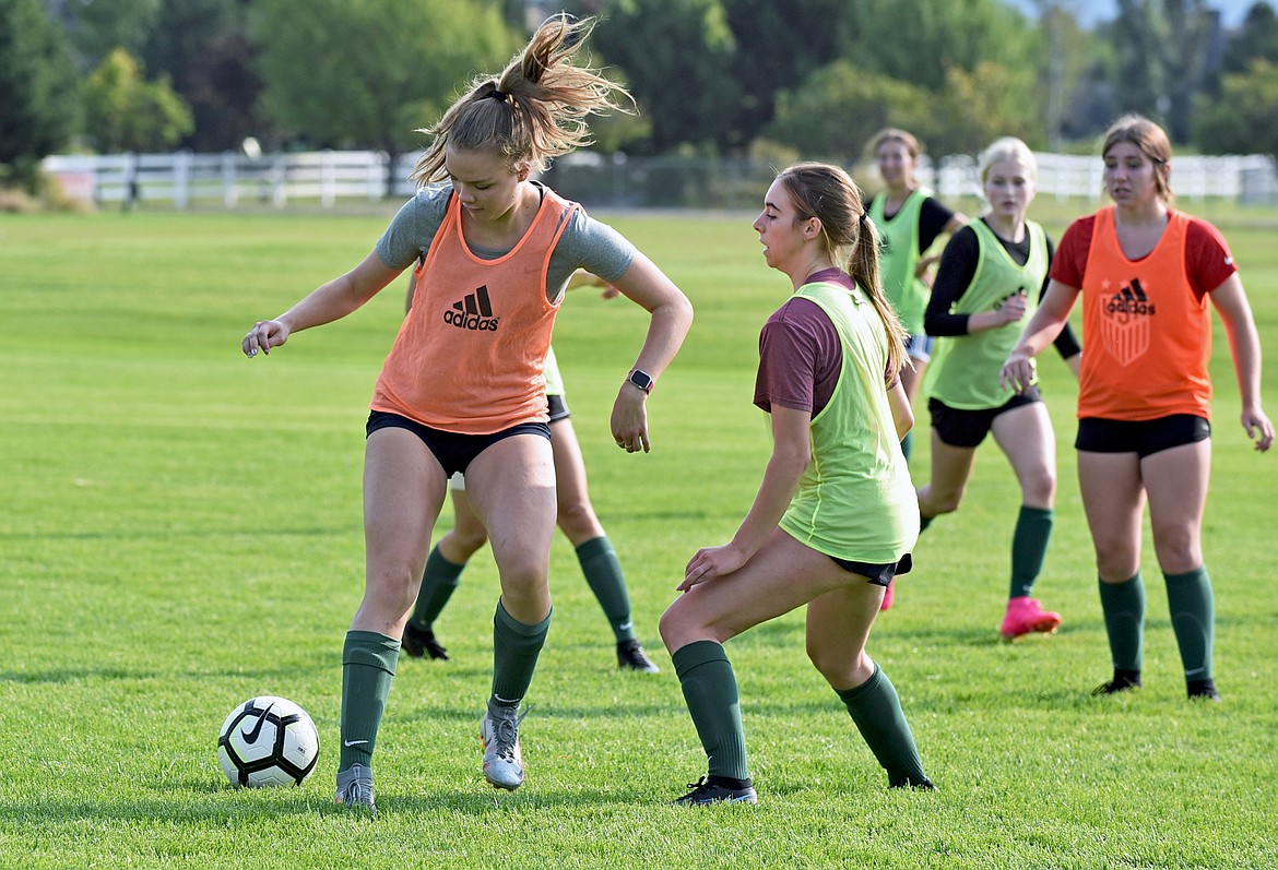 Whitefish players Olivia Genovese, left, and Maddie Muhlfeld, right, play with their team during a girls soccer practice at Smith Fields on Thursday morning. (Whitney England/Whitefish Pilot)