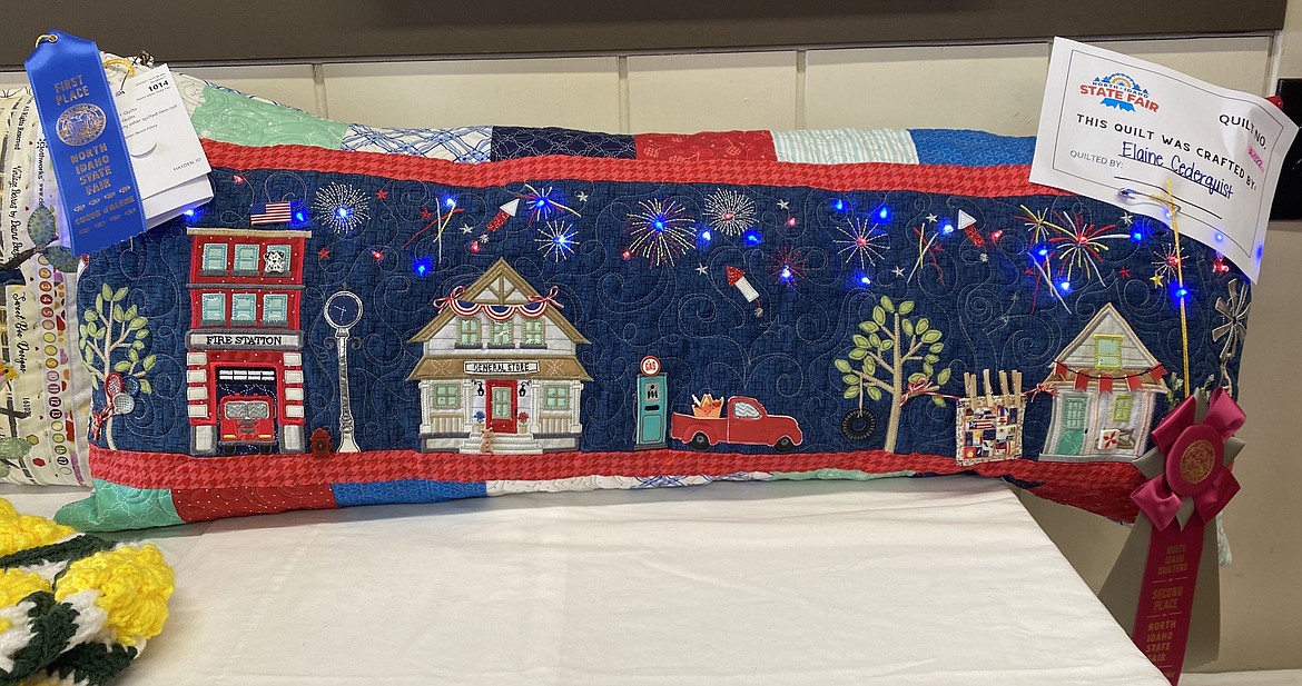 The Fourth of July pillow by Elaine Cederquist features blinking LED lights and a festive scene created from hand applied miniature elements.