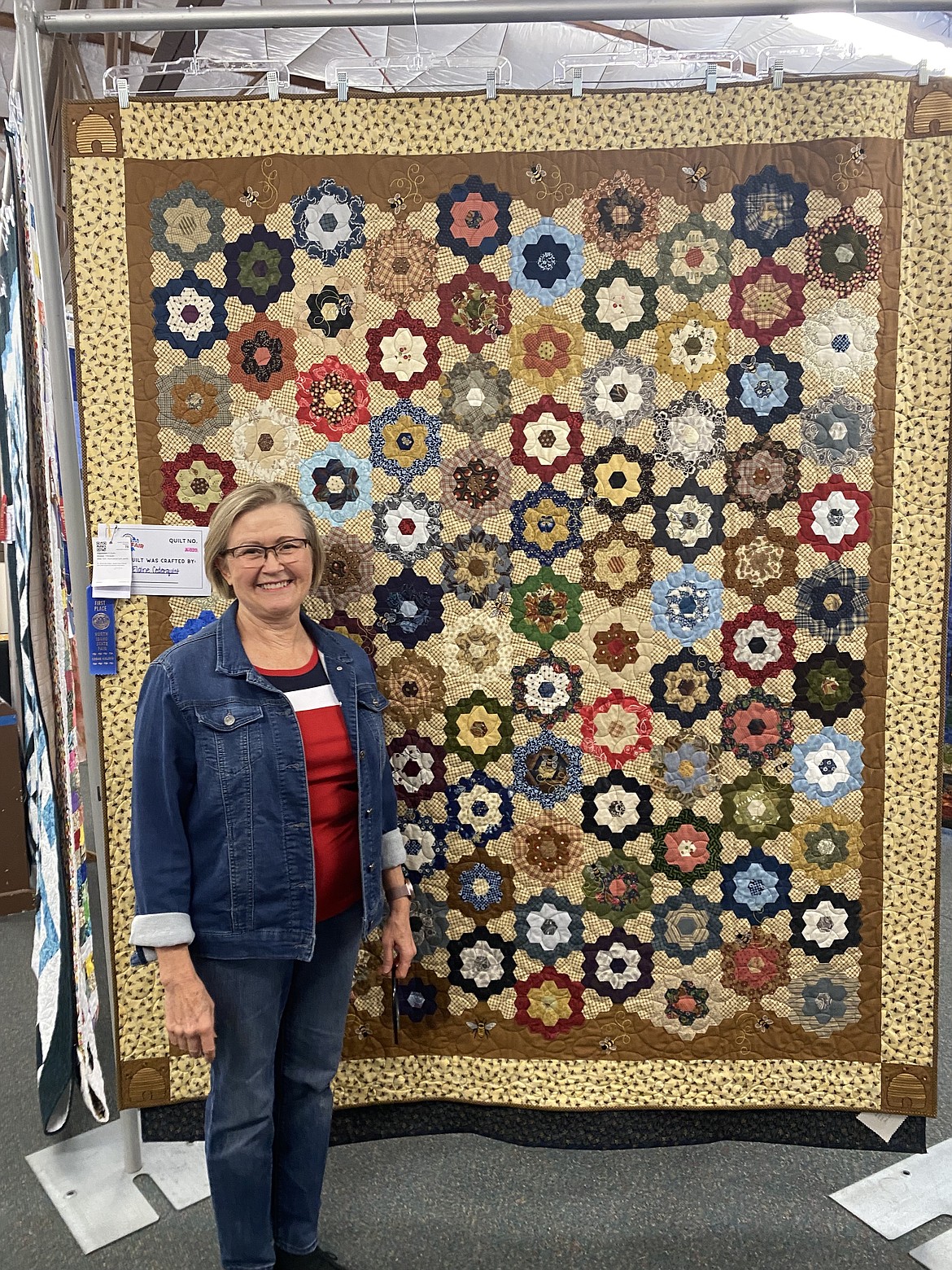 Wednesday at the North Idaho State Fair, Elaine Cederquist stands next to her quilt "The Secret Life of Bees." A hand-pieced design, it required more than 2,200 hand-cut and stitched hexagon pieces and five years to complete.