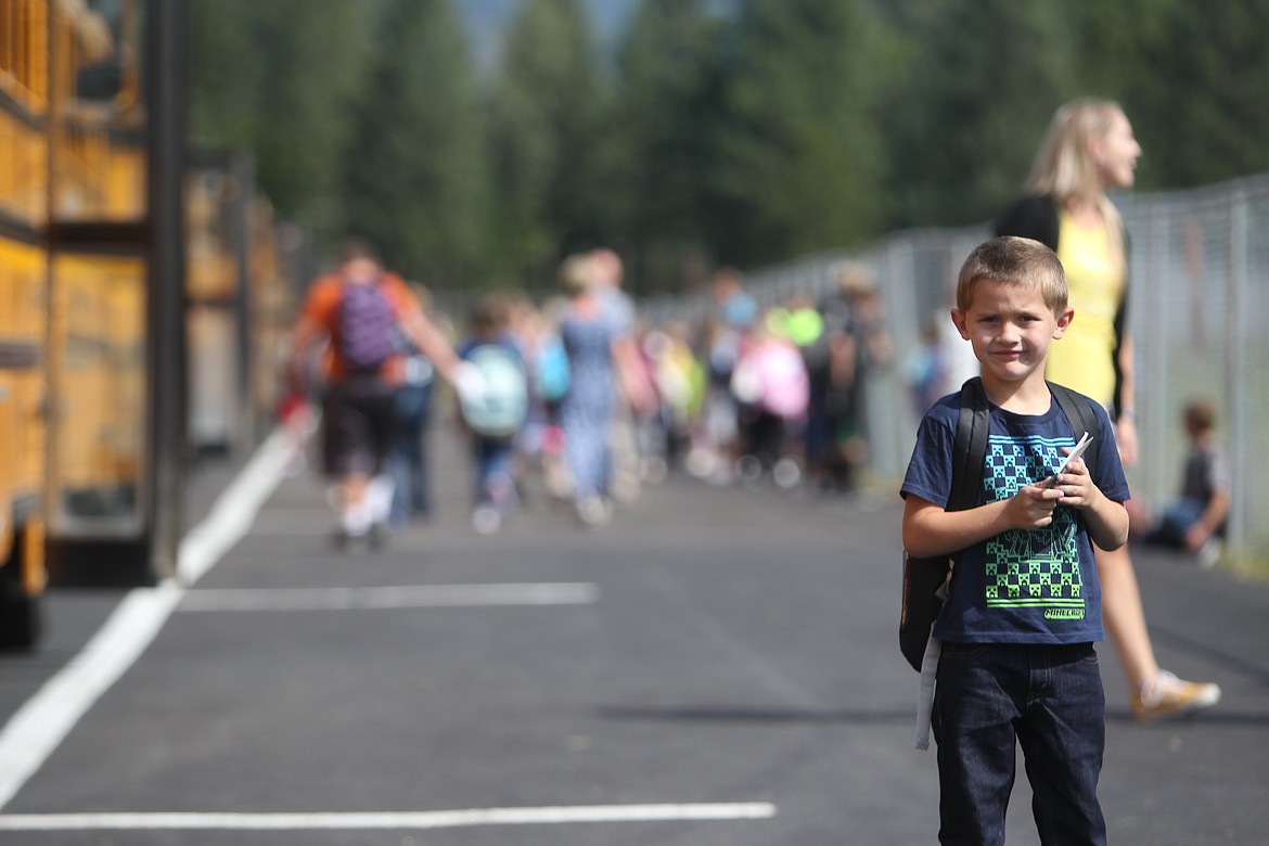 A Libby Elementary School student stands in front of a row of buses after the first day of classes on Aug. 25. (Will Langhorne/The Western News)