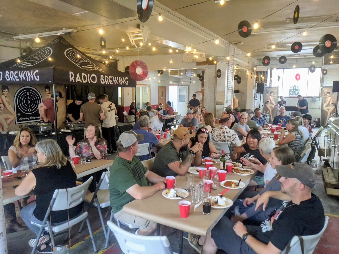 Attendees of the 2nd annual Firefighters Community Fundraiser enjoy their dinner and drinks, served inside the former SCFD No. 2 building in uptown Kellogg on July 24.