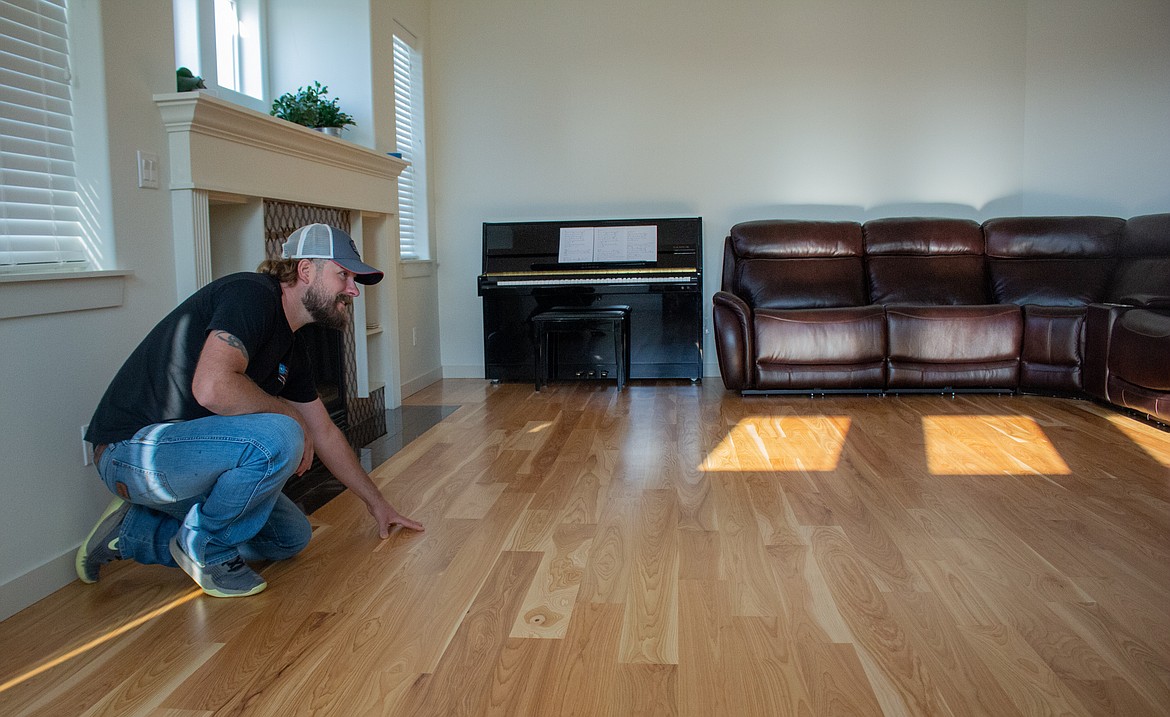 Justin Stromberg kneels beside a hardwood floor recently completed in Moses Lake.