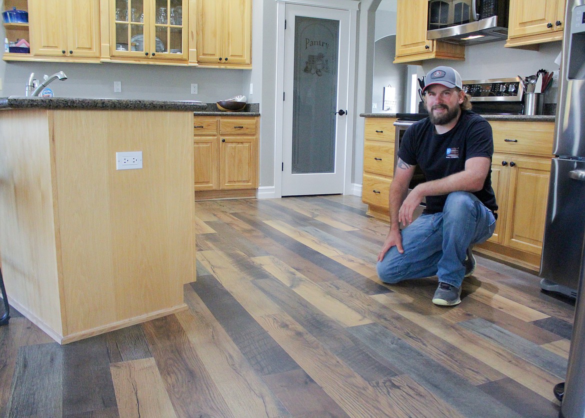 Justin Stromberg kneels in the kitchen on a laminate wood floor recently installed in a home in Moses Lake.