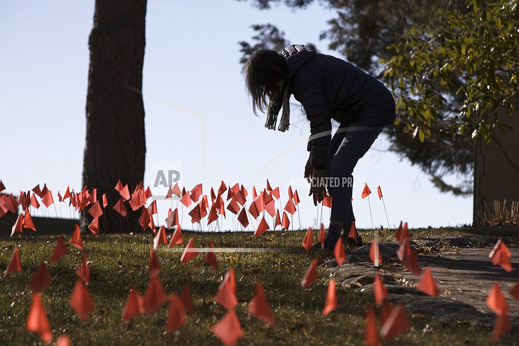 In this Feb. 10, 2021, file photo, Cindy Pollock does maintenance on the construction flags in her front yard in Boise, Idaho. Pollock began planting the tiny flags across her yard, one for each of the more than 1,800 Idahoans then killed by COVID-19, the toll was mostly a number. Idaho hospital facilities and public health agencies are scrambling to add capacity however they can as the number of coronavirus cases continue to rise statewide. On Thursday, Aug. 26, 2021, some Idaho hospitals only narrowly avoided enacting "crisis standards of care," where scarce healthcare resources are allotted to the patients most likely to benefit, thanks in part to statewide coordination. (AP Photo/Otto Kitsinger, File)