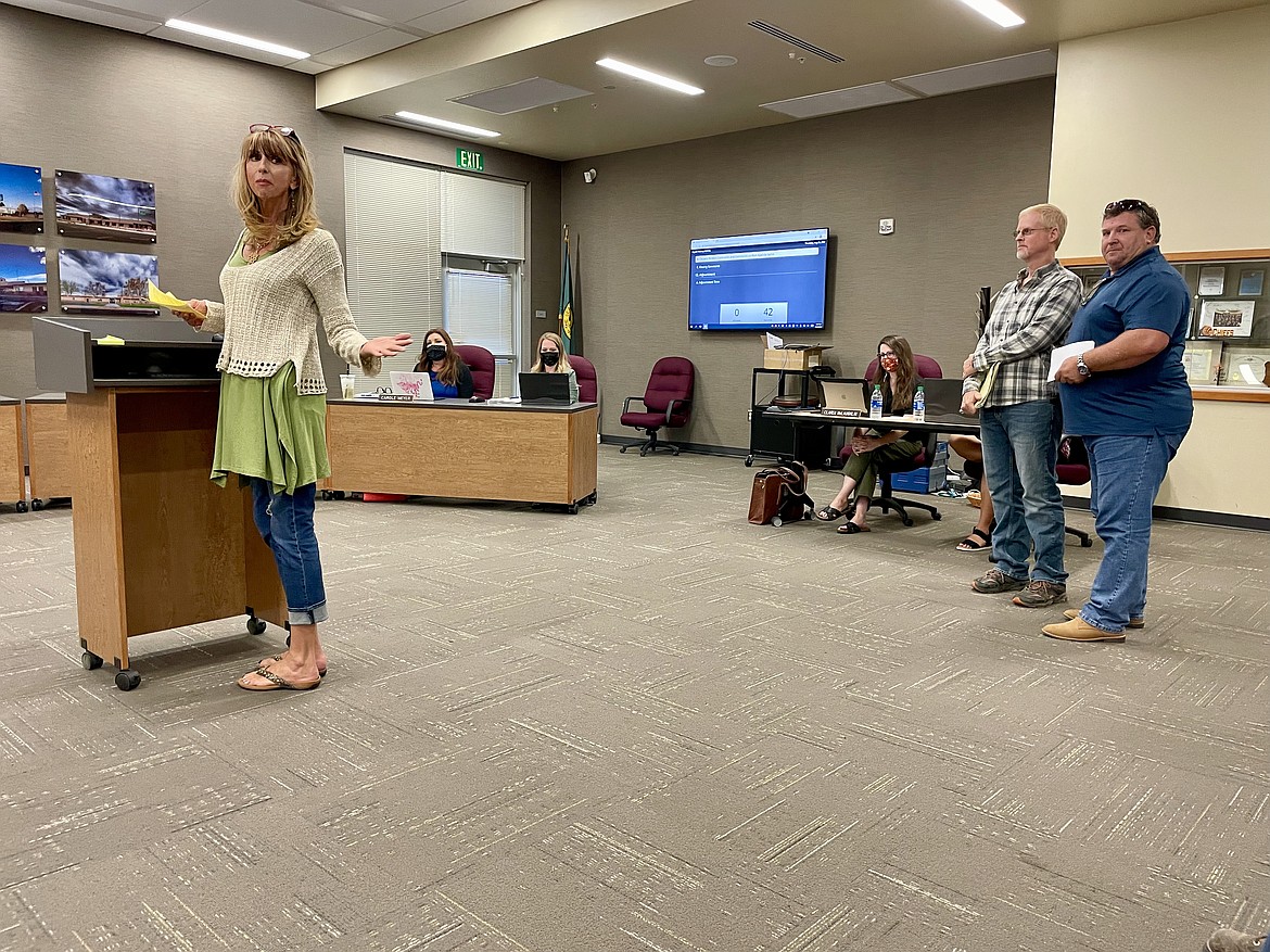 Robin Fode, at left, stands to address members of the Moses Lake School Board and the audience, while Dan DeLano and David Hunt stand and wait, during a regular meeting of the Moses Lake School Board on Thursday.