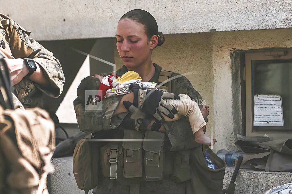 In this Aug. 20, 2021, image provided by the U.S. Marine Corps, Marines assigned to the 24th Marine Expeditionary Unit (MEU), including Sgt. Nicole Gee calms an infant during an evacuation at Hamid Karzai International Airport in Kabul, Afghanistan. Officials said Aug. 28, that Gee of Sacramento, Calif., was one of the Marines killed in Thursday's bombing at the airport. (Sgt. Isaiah Campbell/U.S. Marine Corps via AP)