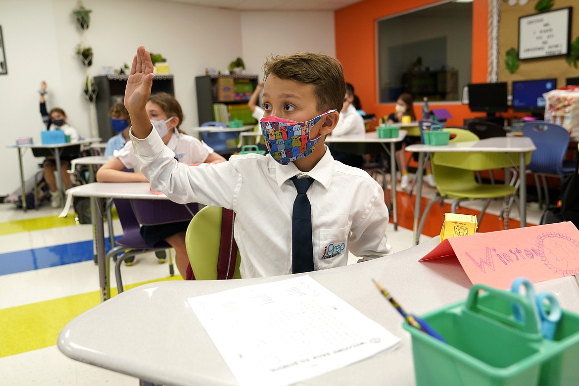 In this Monday, Aug. 23, 2021, file photo, student Winston Wallace, 9, raises his hand in class at iPrep Academy on the first day of school in Miami. A judge has ruled that Florida school districts may impose mask mandates. Leon County Circuit Judge John C. Cooper on Friday agreed with a group of parents who claimed in a lawsuit that Gov. Ron DeSantis' ban on the mandates is unconstitutional and cannot be enforced. (AP Photo/Lynne Sladky, File)