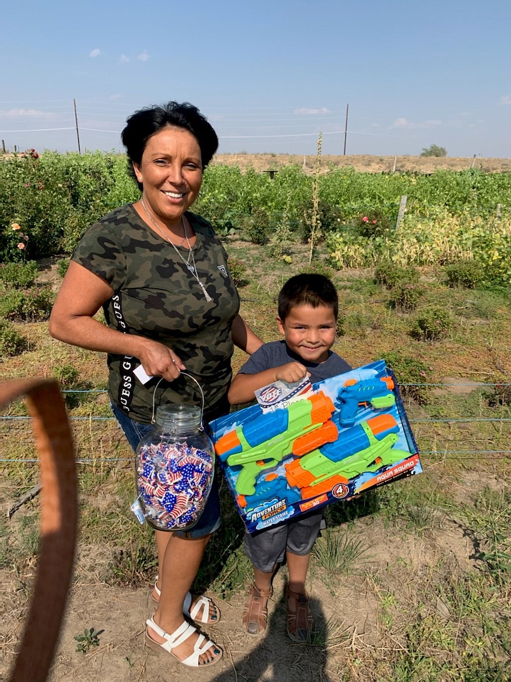 Leticia Garay and her son show their prizes of a large jar of candy and a water blaster for guessing the closest to the number of candies in the jar. This contest was offered by the Grant County Democrats at the Grant County Fair.