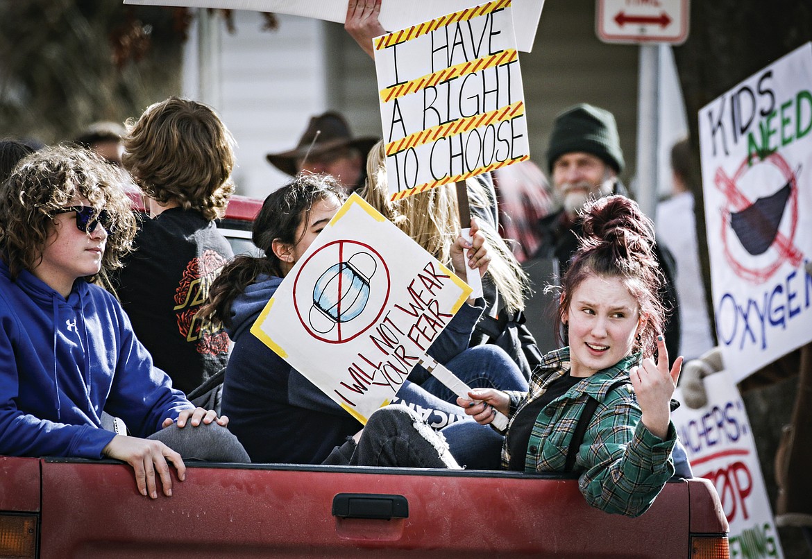 In this March 9, 2021, file photo, students with signs ride in the back of a pickup truck around Flathead High School to protest the Kalispell School District's face mask requirement in Kalispell, Mont. Montana Gov. Greg Gianforte announced on Tuesday, Aug. 31, 2021 a rule encouraging schools to give parents final say on whether children should wear masks in schools, after several large school districts in the state implemented mask requirements for all students. (Hunter D'Antuono/Flathead Beacon via AP, File)