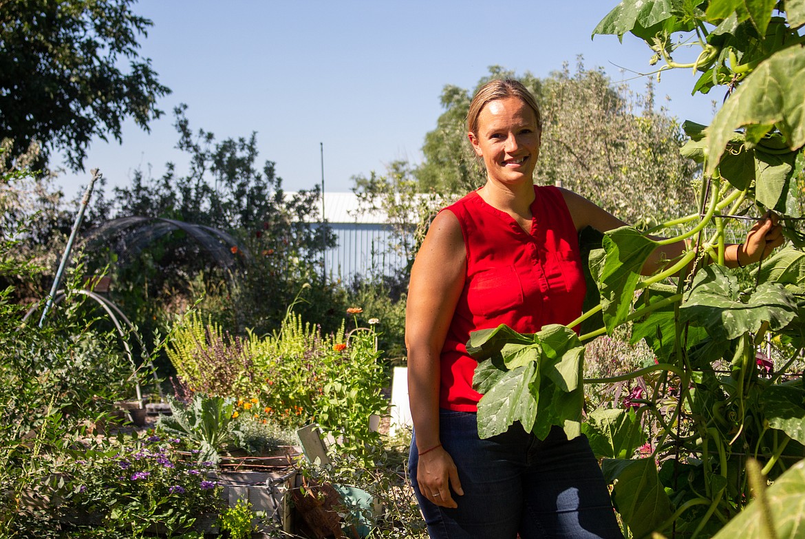 Rhea Flores stands among the variety of vegetables and flowers filling her garden in Moses Lake.