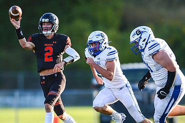 Flathead quarterback Jackson Walker (2) rolls out to throw under pressure from Gallatin's Aidan Martin (9) and Eddie Williams (70) in the first quarter at Legends Stadium on Friday, Sept. 3. (Casey Kreider/Daily Inter Lake)