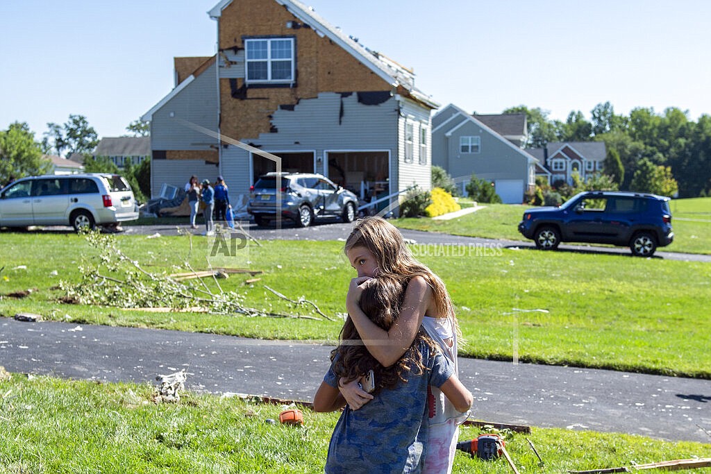 Kenley Thomas, 6, is hugged by her neighbor Natalie Bonnenberg, 12, Thursday, Sept. 2, 2021 after homes in Mullica Hill, N.J. were damaged by a tornado. A stunned U.S. East Coast woke up Thursday to a rising death toll, surging rivers and destruction after the remnants of Hurricane Ida walloped the region with record-breaking rain, filling low-lying apartments with water and turning roads into car-swallowing canals. (Joe Lamberti/Camden Courier-Post via AP)