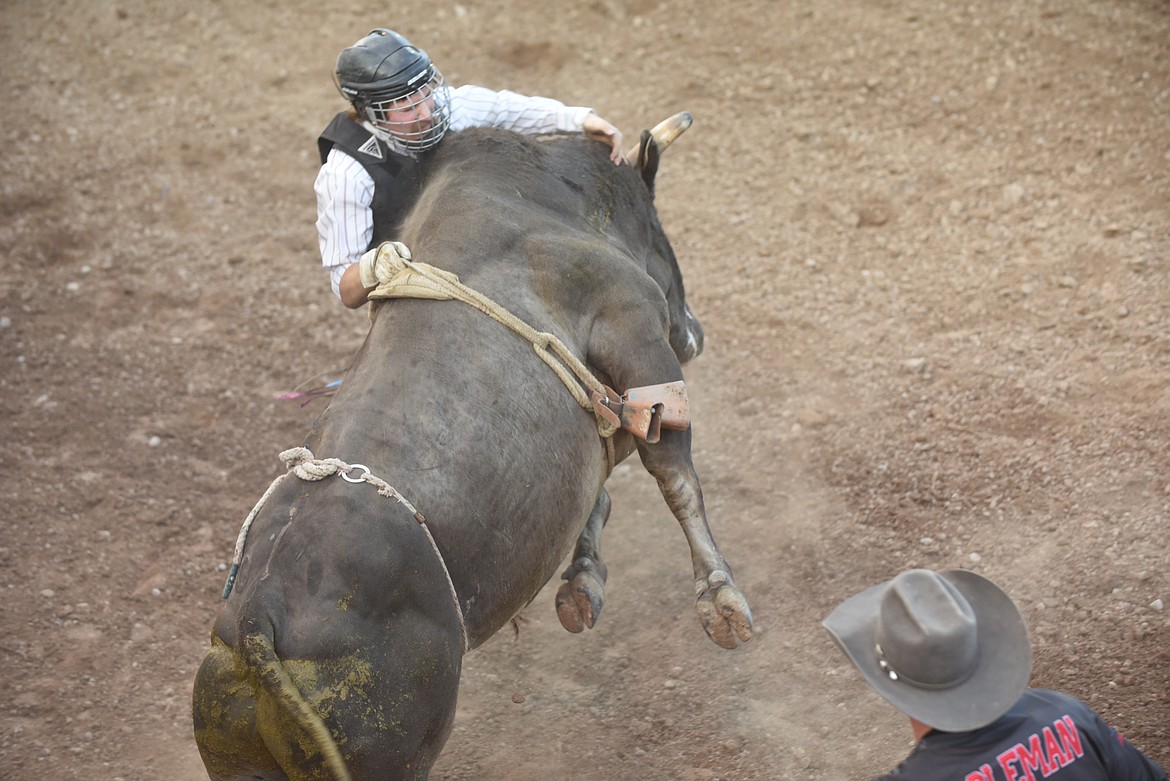 Plains’ Bryce Henning does all he can do to hang on during Thursday night’s bull riding event at the Sanders County Fair.(Scott Shindledecker/Valley Press)