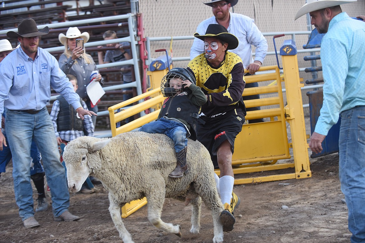 Famed rodeo clown Denny Halstead gives Plains’ Maverick Mull a helping hand during the mutton bustin’ Thursday at the Sanders County Fair. (Scott Shindledecker/Valley Press)