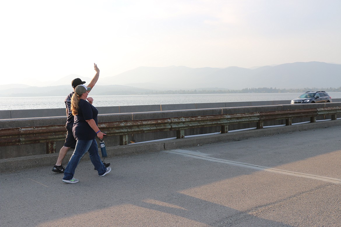Brandon and Dana Bowen wave to passing motorists as they walk across the Long Bridge during the Walk for HOPE on Sunday.