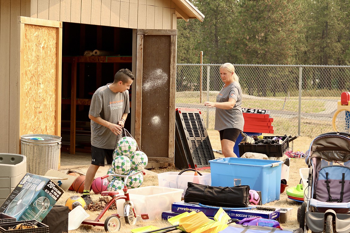 First Interstate Bank Riverstone branch employees Chris Vignale, left, and Toni Capaul, bank manager and board member of the Children's Village, organize a shed at the nonprofit children’s residential care facility in Coeur d'Alene for the annual bank volunteer day on Wednesday afternoon. HANNAH NEFF/Press