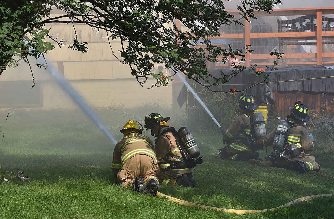 Firefighters spray water on a house off River Lakes Parkway Thursday morning. (Heidi Desch/Whitefish Pilot)