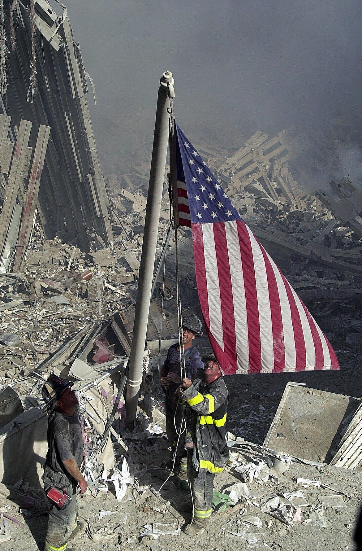 New York City firefighters raise a flag from the rubble of the World Trade Center Tuesday, Sept. 11, 2001. Two hijacked airliners were crashed into the twin towers by terrorists and subsequently collapsed killing and injuring both the trapped and the rescuers.