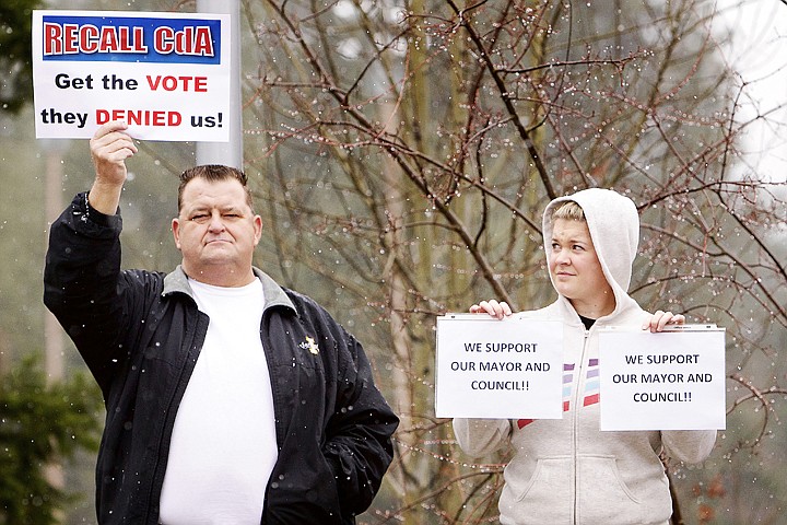 Jennifer Drake, right, and Michael Sheneman hold signs with opposite opinions during a Recall CdA rally on Wednesday (April 4, 2012) at City Hall.