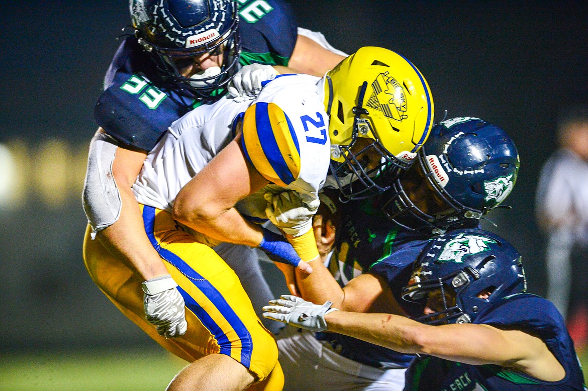 Glacier defenders Jake Rendina (33), Wyatt Thomason (24) and Jake Turner (32) swarm Missoula Big Sky running back Kolbe Jensen (27) in the third quarter at Legends Stadium on Friday, Sept. 10. (Casey Kreider/Daily Inter Lake)