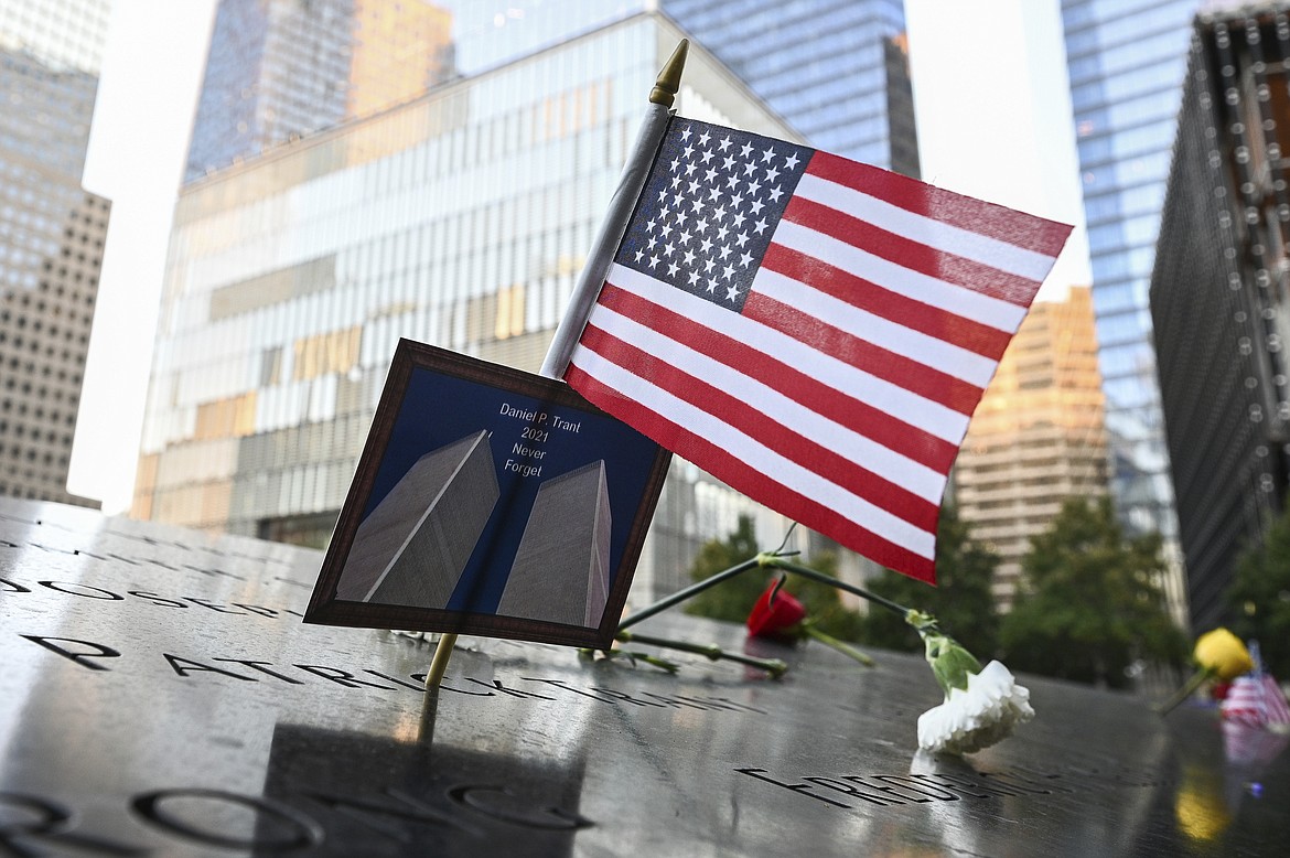 An American flag placed along with a photo of the Twin Towers and the name Daniel P. Trant, a Cantor Fitzgerald bond trader who died during 9/11, before ceremonies to commemorate the 20th anniversary of the Sept. 11, 2001, terrorist attacks, on Saturday, Sept. 11, 2021, at the National September 11 Memorial & Museum in New York. (Anthony Behar, pool photo via AP)