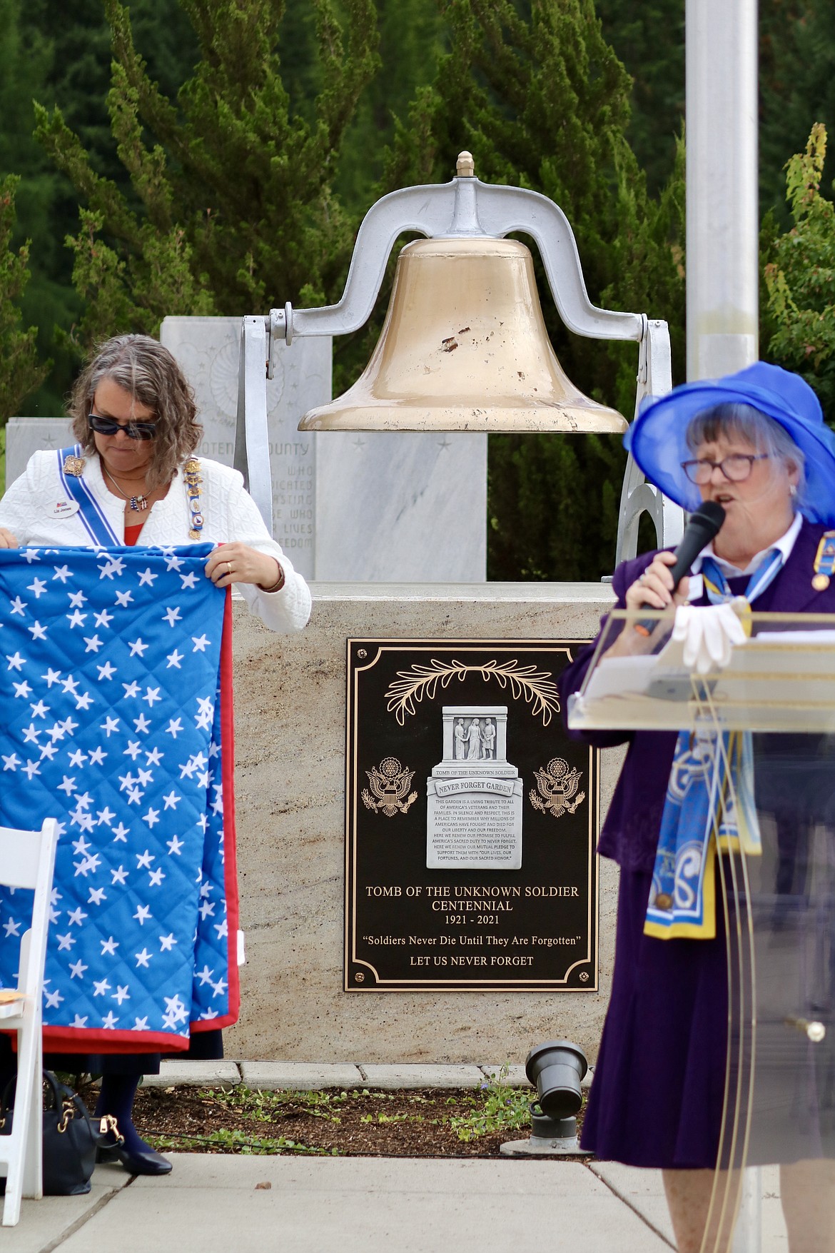 The plaque to commemorate the 100th anniversary of The Tomb of the Unknown Soldier is mounted to "Pappy's Bell" at the Veterans Memorial in McEuen Park in downtown Coeur d’Alene. From left, Elizabeth Jones of Post Falls, Honorary Idaho State Regent of the National Society Daughters of the American Revolution, and Sandra Coultrap, President of the Edward Carleton Chapter, National Society Colonial Dames of the 17th Century at the ceremony on Saturday. HANNAH NEFF/Press