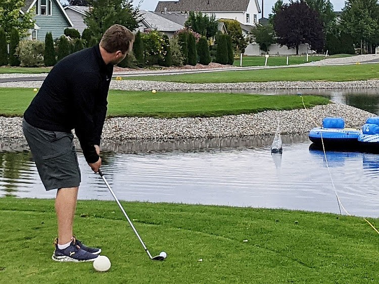 Golfer Drew Harris lines up in an attempt to chip a ball into floating boats during the Boat Shoot Competition.