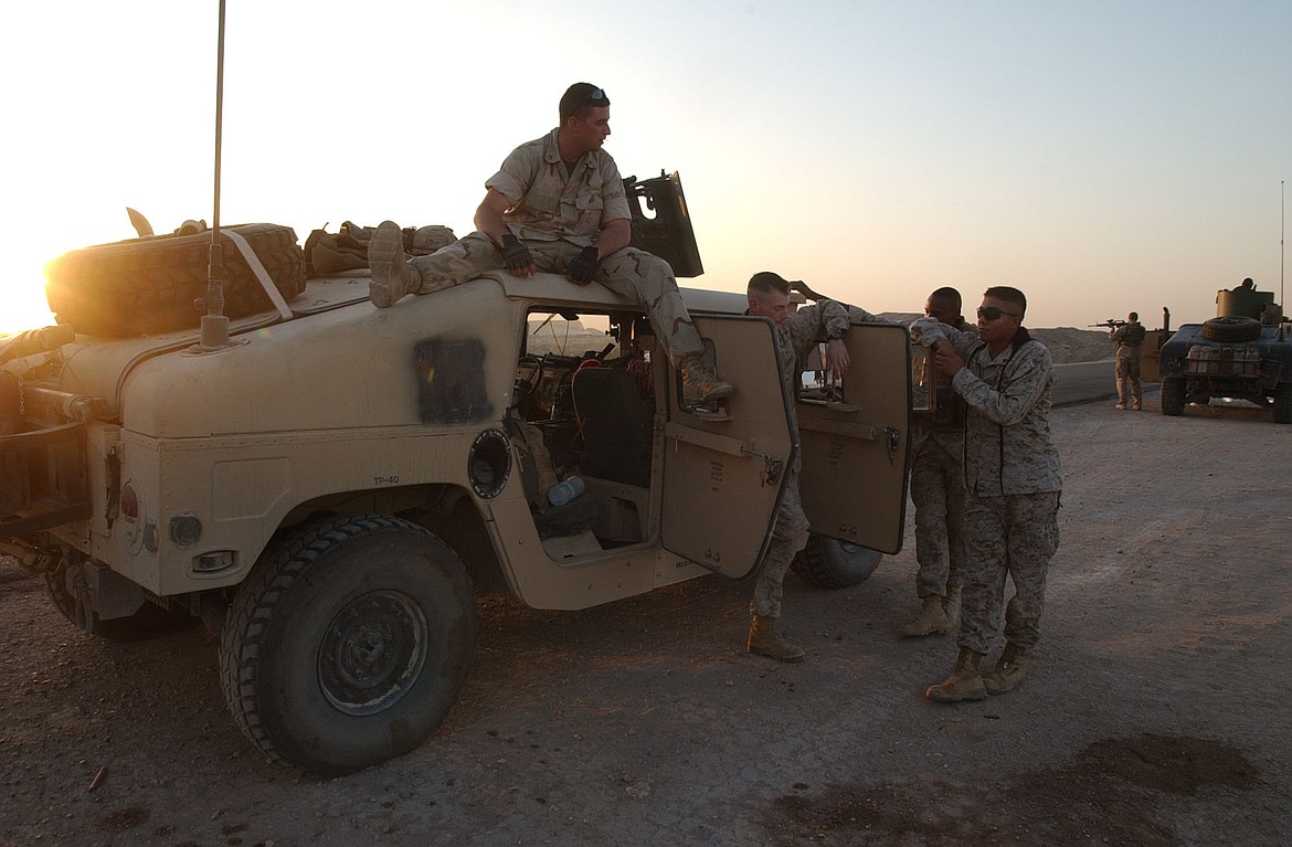 A convoy security team consisting of Lance Cpl. Chris Musick on top of the Humvee, Cpt. Steven "Skinny" D. Jordan and Lance Cpl. Arthur Morales are seen at a staging area before leaving for Fallujah.