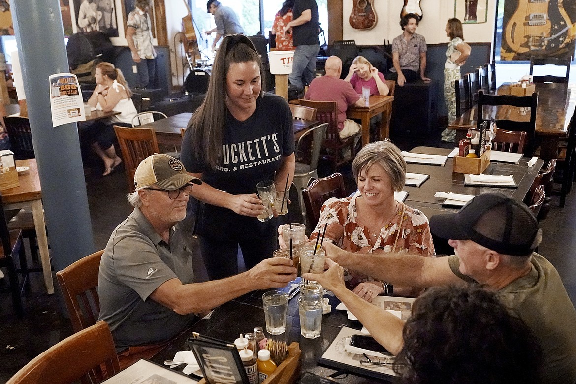 Macy Norman, center, serves a table of guests at Puckett's Grocery and Restaurant on Friday, Sept. 10, 2021, in Nashville, Tenn. In Nashville, tourism has come back faster than downtown office workers following Covid-19. Nashville's reputation as a tourist destination is buoying restaurants while businesses in other downtown areas have had to adapt as offices remained closed and workers stay home. (Mark Humphrey/Associated Press)