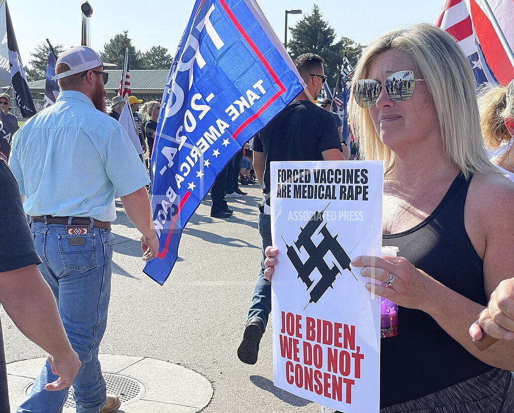 Michelle Ballon, of Caldwell, Idaho, holds up a sign and joins protesters outside the National Interagency Fire Center in Boise, Idaho, as they gather for President Joe Biden's arrival on Monday, Sept. 13, 2021. Biden's stop in Boise is part of a swing through Western states in which he will promote his administration's use of a wartime law to aid in wildfire preparedness. (AP Photo/Keith Ridler)