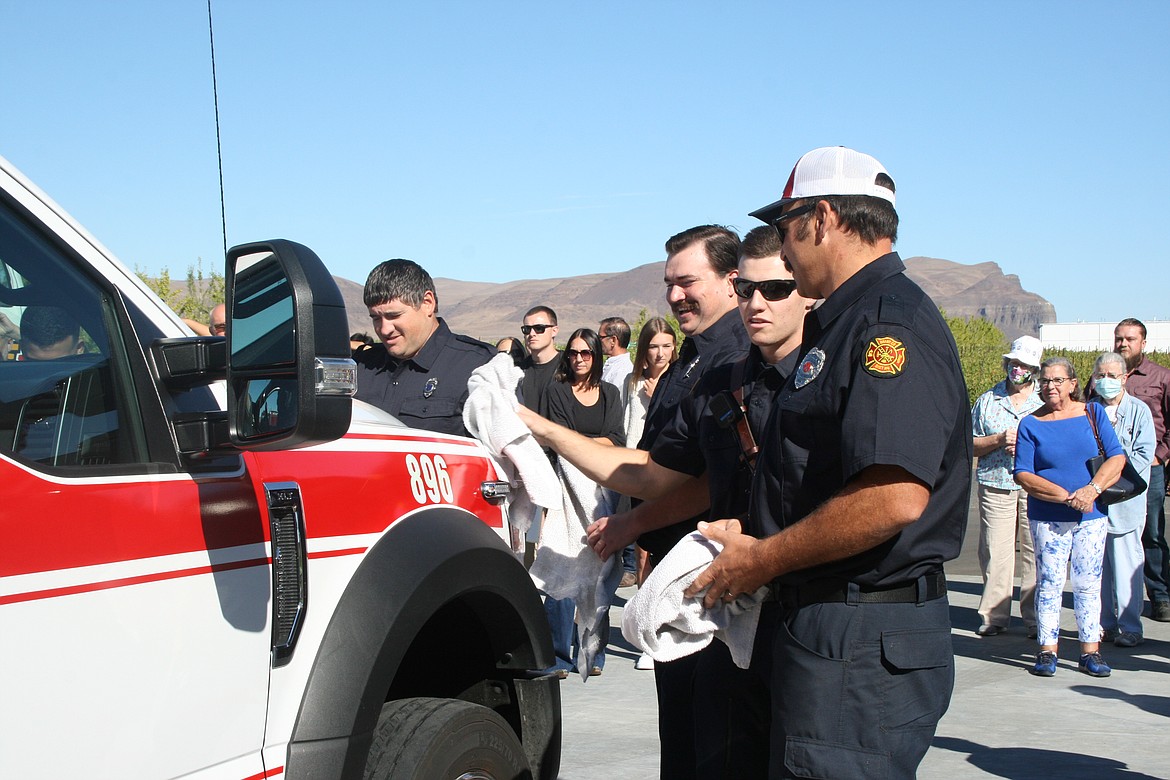 (From left) Ross Massey, Grant Parfitt, Zach Feist and Matt Hyndman dry off the new Grant Fire District 8 ambulance before pushing it into the district’s new fire station.