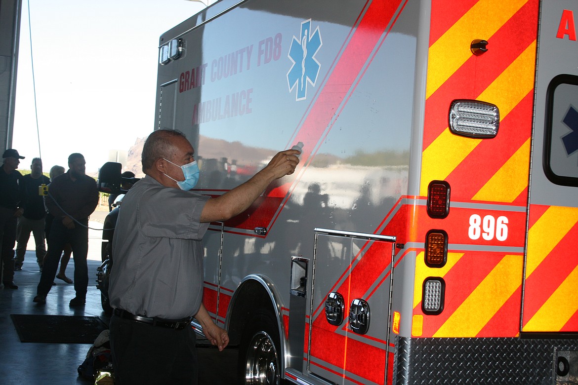 Father Alex Trejo of Our Lady of the Desert Parish sprinkles holy water on a Grant County Fire District 8 ambulance during dedication of the district’s new station.
