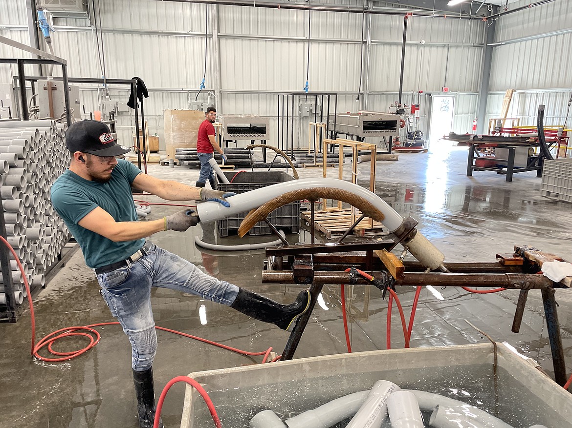 A Raceways Technology employee shows how a large PVC pipe is bent.