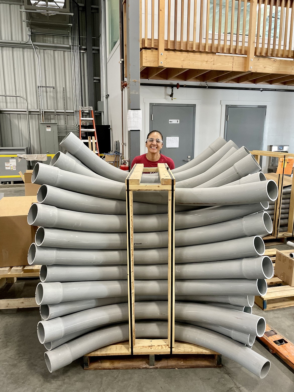 Kara Negrete, who oversees shipping for Raceways Technology in Quincy, works with a stack of PVC pipes in a custom-built storage and shipping rack.