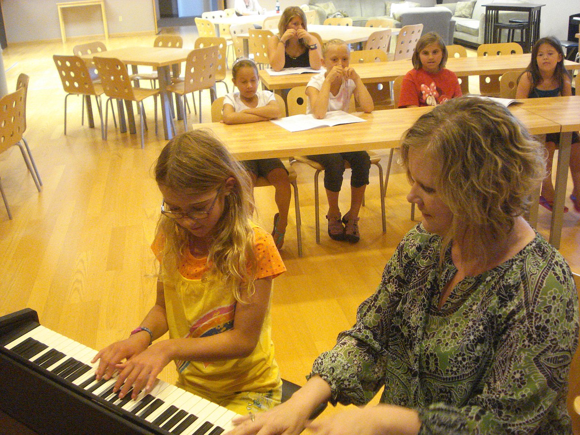 Mary Loeffelbein works with some young musicians while sitting at the piano. Loeffelbein teaches piano, voice lessons, songwriting and improvisation techniques at her Ephrata music studio.