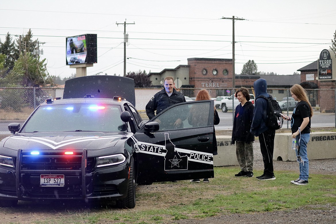 Idaho State Trooper Bryan Mashtare shows Lake City High School students from left, Natilly Prochaska, Christian Cole-Acevedo, Samuel Prochaska and Ashlynn Swing the inside of a trooper car at Meet the Machines at the Kootenai County Fairgrounds on Saturday morning. HANNAH NEFF/Press