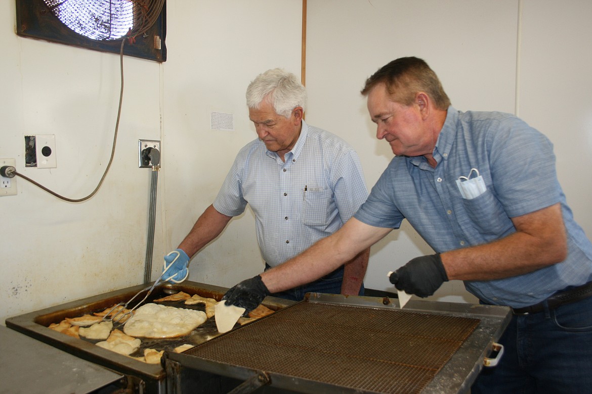 Brad Kent (left) tends the elephant ears while Randy Roylance adds more dough at The Church of Jesus Christ of Latter-day Saints booth.