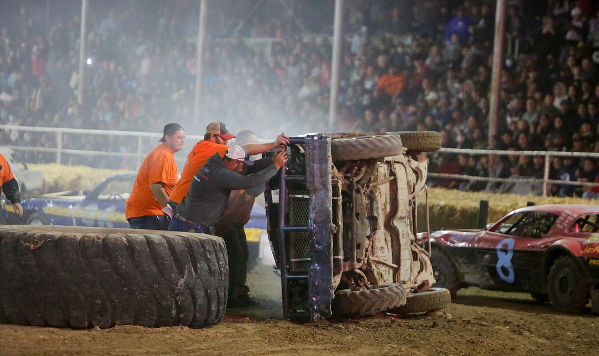 Othello Demolition Derby crew members work to flip over a car on the track during a race Wednesday night at the Adams County Fairgrounds.