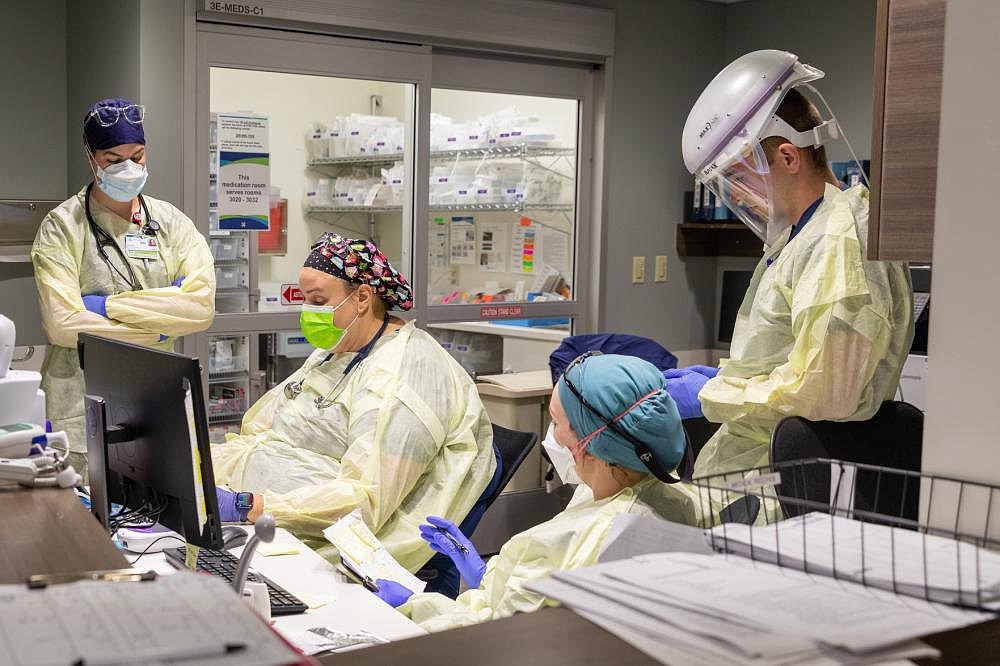 U.S. Army 1st Lt. Blaine Woodcock, a critical care nurse assigned to the 627th Hospital Center, right, and Kootenai Health regional medical center employees discuss patient treatment plans during the COVID response operations at the hospital on Wednesday. (U.S. Army Photo by Sgt. Kaden D. Pitt)