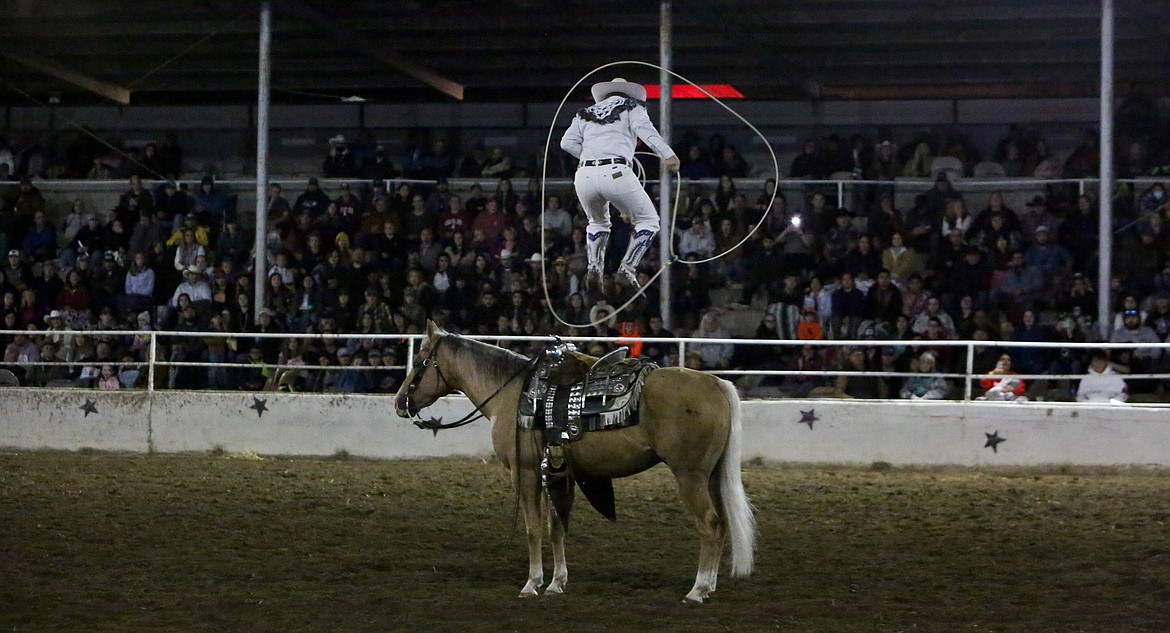 Entertainer Rider Kiesner leaps inside his own rope while standing atop his horse inside the Othello arena on Saturday night.